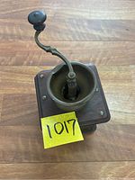 Top view of antique coffee grinder showing metal crank handle with wooden knob and metal funnel