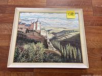 Full view of the framed oil painting showing a castle with countryside and mountain background.