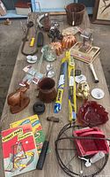 Wide view of the table with all items spread out showing diverse types of lot contents including tools, figurines, books, and household items.