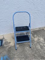 Front view of two-step ladder showing blue frame and black steps.