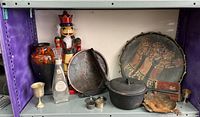 Shelf with nutcracker figurine, glass bottle, decorative vase, cast iron pot, salt and pepper shakers, and other items