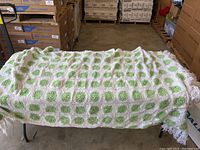 White and green crocheted afghan blanket displayed on a table