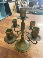 Five-arm brass candelabra showing front view with spotting and oxidation on brass surface.