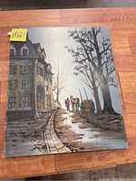 View of the original mixed media painting showing a street scene with people walking along a cobblestone path with buildings and trees.