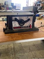 Side view of Skilsaw table saw showing the brand label, blade angle adjustment handwheel, and base.