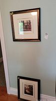 Two framed prints hanging on wall, top and bottom