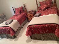 Two twin wooden bed frames with floral bedding, bed skirts, blankets, and cushions