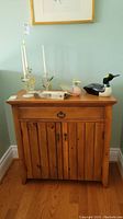 Front view of the solid wood cabinet with drawer and two doors, displaying decorative items on top.