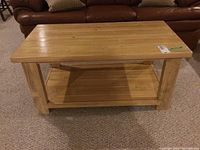 Front view of the wood coffee table showing natural wood plank top and shelf under the table surface, solid square legs.