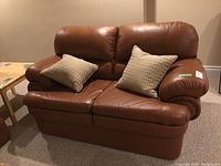 Front view of loveseat with two throw cushions showing overall condition
