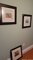 Three framed prints displayed on wall and floor