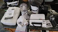 Overview of the lot including the hand mixer, mini food processor, SodaStream with bottle, sandwich maker, and food sealer on a kitchen counter.