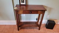Front angled view of wooden side table showing drawer and lower shelf