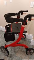 Front view of red frame rollator walker showing four wheels, Nitro branding on side