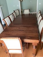 Full view of walnut dining table assembled with three leaves and 12 chairs