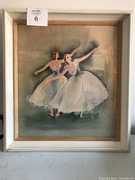 Framed painting showing two ballerinas in white tutus posed mid dance with soft green background.