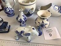 Overview of the front assorted Delft Blue items including elephant figurine, small vases, and hollow pot with holes.