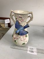 Front view of Fitz & Floyd vase showing textured basket weave surface, 3D flowers, and bluebird in mid-flight.
