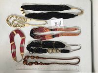 Photo of the full lot showing six vintage beaded necklaces in various styles and colors lying flat with a ruler for size reference.