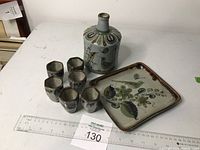 Full view of decanter with cork stopper, six shot glasses, and rectangular tray arranged with measuring ruler