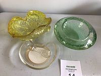 Photo showing the three Murano glass items: yellow ashtray/bowl with textured edges, green bullicante bowl with bubbles, and clear & gold mortar with pestle inside.