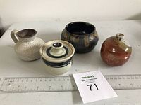 Four small pottery pieces shown with rulers for size reference, including different shapes and colors