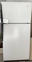 Front exterior view of white Amana refrigerator with top freezer