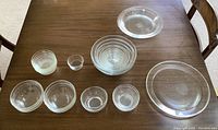 Top-down view of 9 glass bowls and large glass platter on table