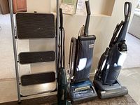 Photo showing Rubbermaid 3-step stool alongside Hoover Legacy, Kenmore Progressive, and Eureka SuperBroom vacuums.