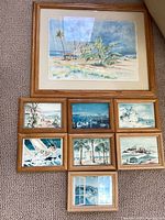 Original watercolor painting at top showing beach, palm trees, and sky. Below are eight smaller prints each with wood frames, depicting various Laguna Beach coastal and marine scenes.