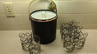 Full set showing ice bucket and six matching glasses with black and gold lattice design on a kitchen countertop