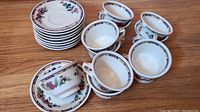 Overview of full set with stacked saucers and cups arranged around them showing decorative pattern