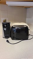 Black and Decker toaster and Kitchen Living can opener side by side on countertop.