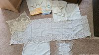 Photo showing lace table runner in center with crocheted doilies, tea towels and napkins around it.