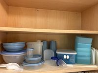 Shelf with several vintage Tupperware pieces in blue and white including bowls, cups, and rectangular containers