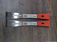 Two new 10 inch mini pry bars placed on a wooden floor, showing the full length, metal ends and partially orange painted handles.