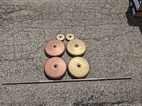 Barbell laid out horizontally with all weight plates arranged above it on pavement.