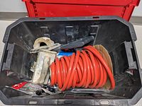 Top view inside the Husky stackable tote showing orange air hose, metal trowels, and small tools