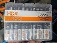 Clear plastic case holding 48 HDX brand AAA alkaline batteries. Label on case indicates long-lasting national brand batteries with a 10-year storage guarantee.