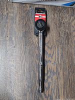 Full view of the Powerbuilt 1/2 drive ratchet showing the metal body and black plastic ratchet head against a wood background.