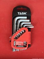 Photo of the 13 L-type hex keys in their red branded Task plastic holder set against a red background.