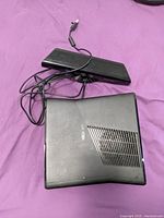 Top view of Xbox 360 console and Kinect sensor with cables on pink surface.