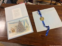 Photo showing the print and accompanying letter alongside a large envelope sealed with a gold presidential seal attached to a blue ribbon, all laid out on a wooden table.