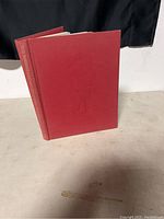 Front cover of the red hardcover book with embossed emblem and slight wear.