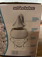 Photo showing the set includes label with diagram pointing to the ceramic cover, ceramic pot, fondue stand, tea light candle, and fondue forks.