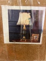 Photo of the lamp on a table showing the lamp base and fabric shade with floral detail.
