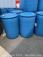 Photo of two blue plastic barrels placed outdoors on pavement, branded for rainwater collection or repurposing.