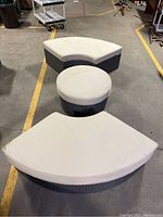 Overview of three piece Sunbrella patio set: two curved seats and round ottoman with off-white cushions.