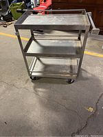 Full view of the three tier stainless steel rolling cart showing all three shelves and caster wheels.
