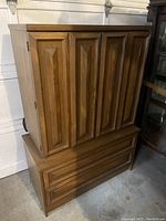 Front view of oak armoire closed showing two large drawers at base and paneled doors above